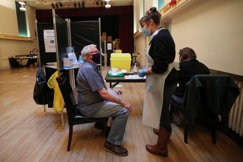 &copy; Reuters. A healthcare worker speaks with an elderly person before administering a dose of the Pfizer-BioNTech coronavirus disease (COVID-19) vaccine at Thornton Little Theatre managed by Wyre Council in Lancashire, Britain January 29, 2021. REUTERS/Molly Darlingto