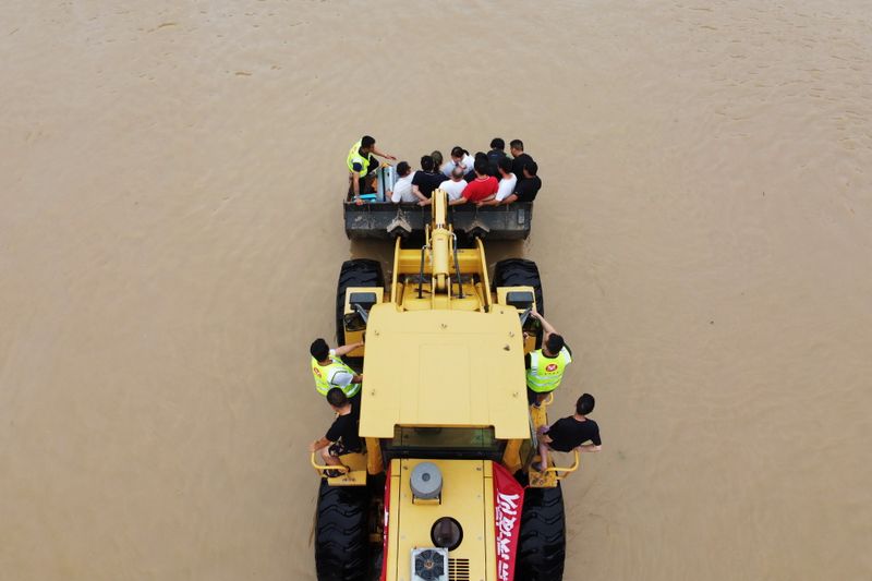 &copy; Reuters. عمال إنقاذ يقومون بنقل السكان العالقين بسبب الفيضانات باستخدام حفارات في مدينة تشينغتشو بإقليم خنان الصيني يوم الجمعة. تصوير: آلي سونغ - روي