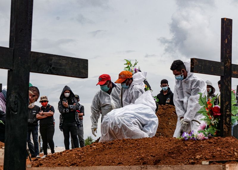 &copy; Reuters. FILE PHOTO: Gravediggers wearing personal protective equipment (PPE) burry a coffin at a burial area provided by the government for coronavirus disease (COVID-19) victims, as cases surge in Jayapura, Papua, Indonesia July 20, 2021, in this photo taken by 