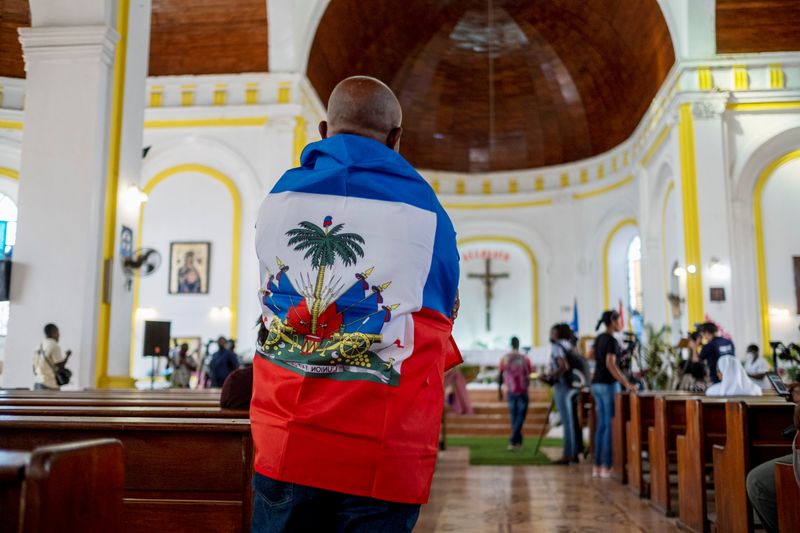 &copy; Reuters. Un hombre envuelto en una bandera haitiana antes del funeral del asesinado presidente Jovenel Moise en la Catedral de Notre Dame de Cabo Haitiano, Haití. 22 julio 2021. REUTERS/Ricardo Arduengo