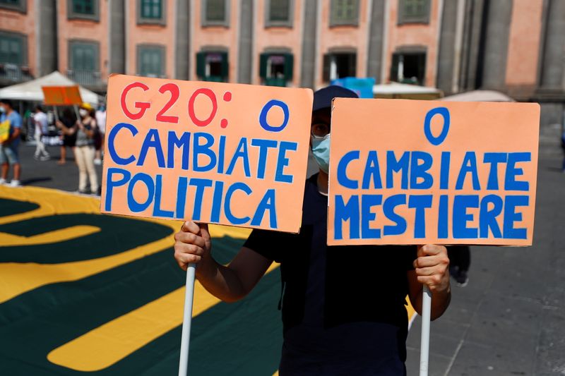 &copy; Reuters. Un manifestante con due cartelli, durante una protesta a Napoli in occasione del meeting del G20. REUTERS/Guglielmo Mangiapane