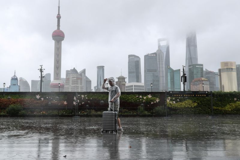 &copy; Reuters. A man with luggage walks in the rain on The Bund as Typhoon In-fa approaches Shanghai, China July 25, 2021. cnsphoto via REUTERS   