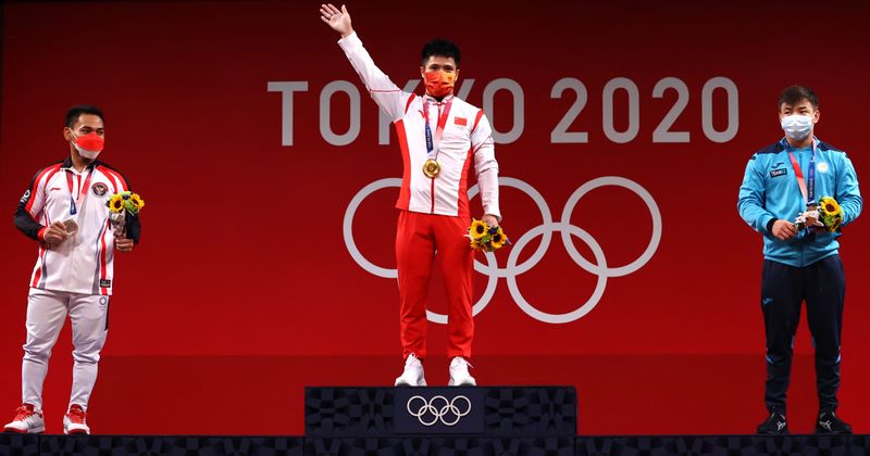 © Reuters. الصيني لي فابين الفائز بذهبية وزن 61 كيلوجراما للرجال في رفع الأثقال بأولمبياد طوكيو 2020 والإندونيسي إيكو يولي إراوان الفائز بالميدالية الفضية والقازاخستاني إيجور سون الفائز بالبرونزية خلال مراسم تقلد الميداليات يوم الأحد. تصوير: إدجارد جاريدو - رويترز.
