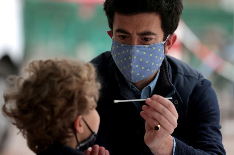 &copy; Reuters. FILE PHOTO: A man takes a swab sample for the coronavirus disease (COVID-19) from his son at a surge testing site in London, Britain, May 14, 2021. REUTERS/Hannah McKay/File Photo