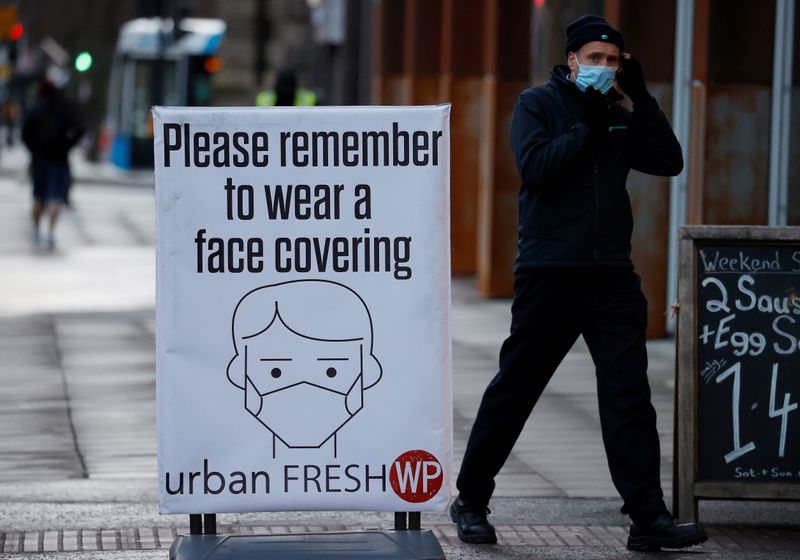 &copy; Reuters. A man walks past a sign encouraging people to wear face coverings amid the COVID-19 outbreak in Belfast, Northern Ireland January 2, 2021. REUTERS/Phil Noble/Files