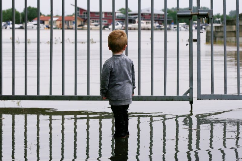 &copy; Reuters. FILE PHOTO: A child looks on as water floods through a fence in Wessem, Netherlands, July 16, 2021. REUTERS/Eva Plevier/File Photo