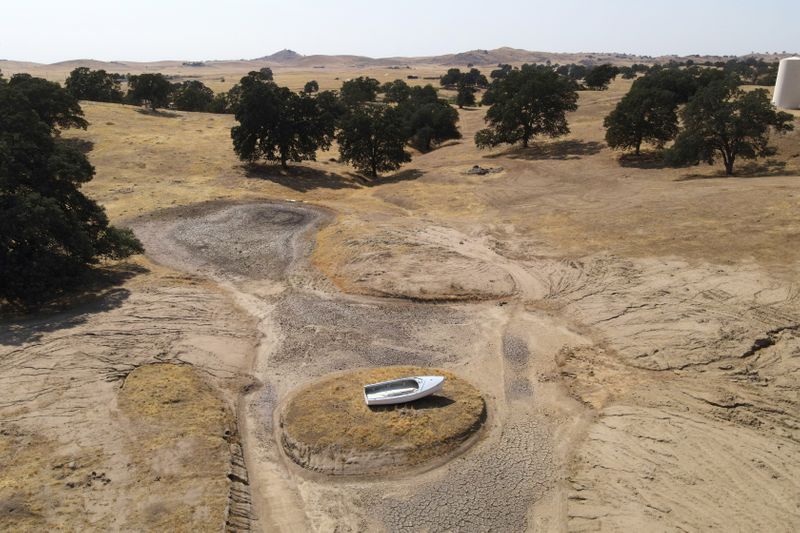 © Reuters. FILE PHOTO: A lone boat sits perched on a mound near Hensley Lake as soaring temperatures and drought continue to affect livestock and water supplies in Madera, California, U.S. July 14, 2021. Picture taken with a drone.  REUTERS/David Swanson/File Photo