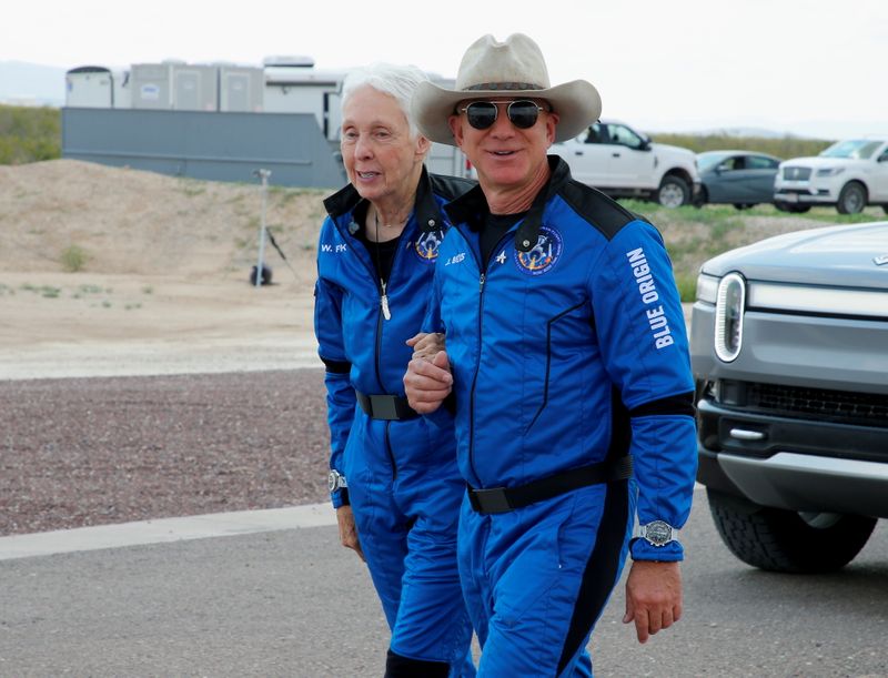 &copy; Reuters. FILE PHOTO: Billionaire American businessman Jeff Bezos walks with crew mate Wally Funk at the landing pad after they flew on Blue Origin's inaugural flight to the edge of space, in the nearby town of Van Horn, Texas, U.S. July 20, 2021. Funk, 82, became 