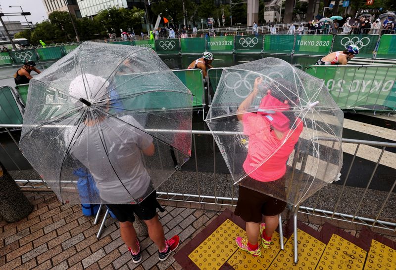 &copy; Reuters. Aficionados y residentes durante la prueba de triatlón femenino bajo la lluvia provocada por la tormenta tropical Nepartak, en el Parque Marino de Odaiba, Tokio, Japón 27 de julio de 2021. REUTERS/Issei Kato