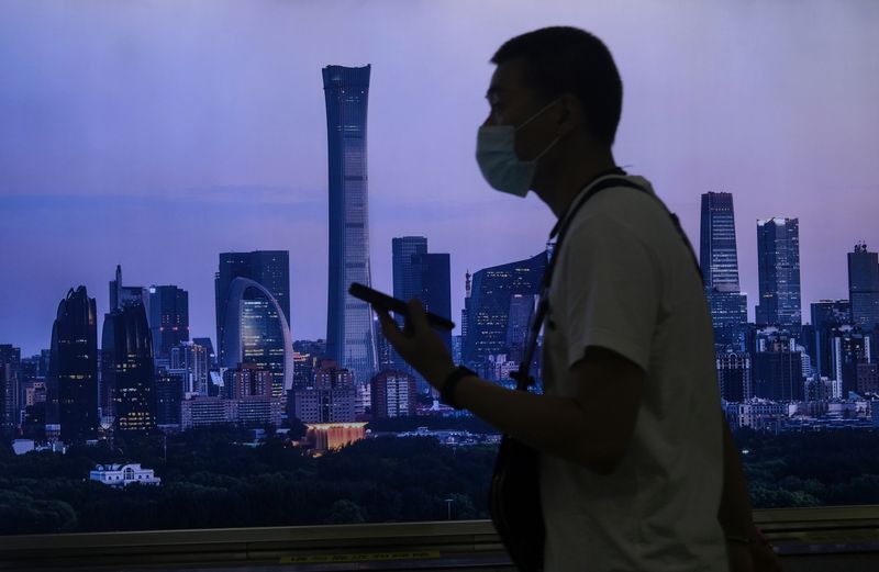 &copy; Reuters. A man wearing a face mask walks past a billboard showing Beijing's city skyline at a subway station, following the coronavirus disease (COVID-19) outbreak, in Beijing, China June 30, 2020. REUTERS/Tingshu Wang/File Photo