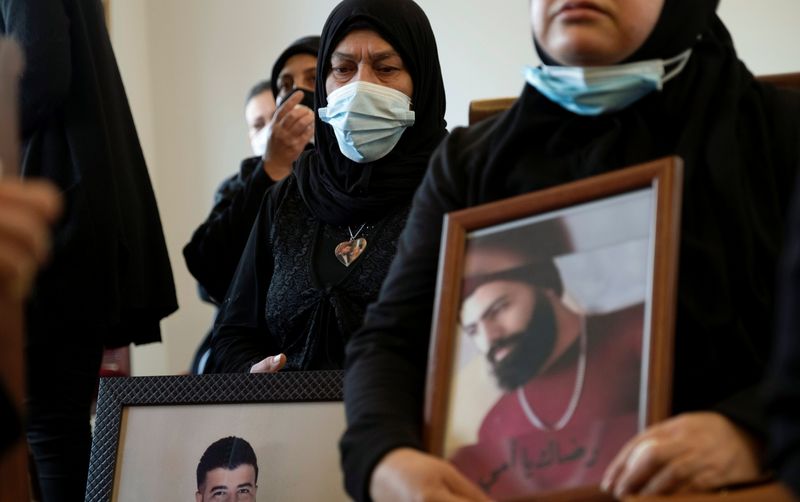 &copy; Reuters. FILE PHOTO: Relatives of victims of Beirut port explosion, hold their pictures during a ceremony in Beirut, Lebanon March 20, 2021. REUTERS/Emilie Madi