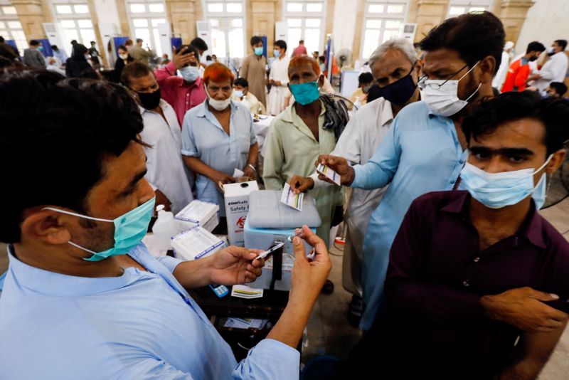 &copy; Reuters. FILE PHOTO: Residents with their registration cards gather at a counter to receive a dose of coronavirus disease (COVID-19) vaccine at a vaccination center in Karachi, Pakistan June 9, 2021. REUTERS/Akhtar Soomro