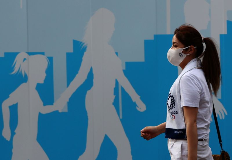 &copy; Reuters. A woman wearing a protective mask, amid the coronavirus disease (COVID-19) outbreak, walks past a fence outside the National Stadium, the main venue of the Tokyo 2020 Olympic Games in Tokyo, Japan, July 28, 2021.   REUTERS/Kim Kyung-Hoon