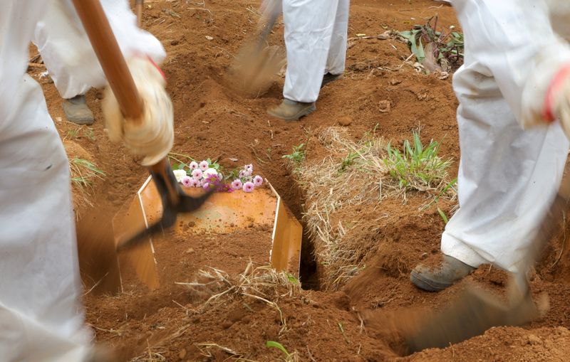 &copy; Reuters. Gravediggers wear protective suits as they work during the burial of Benedito Rodrigues da Silva, 83, who died from the coronavirus disease (COVID-19), at Vila Formosa cemetery in Sao Paulo, Brazil March 17, 2021. REUTERS/Carla Carniel