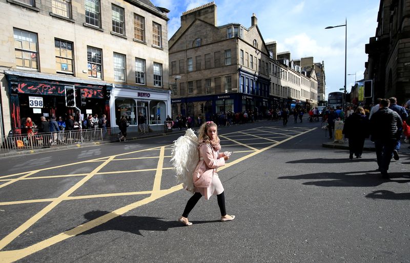&copy; Reuters. FILE PHOTO: A woman wearing angel wings crosses a road during the fringe festival in Edinburgh, Britain. Aug 24, 2018. REUTERS/Jon Super/File Photo