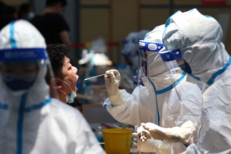 &copy; Reuters. A medical worker in protective suit collects a swab from a resident for nucleic acid testing at a sports centre in Jiangning district, following new cases of the coronavirus disease (COVID-19) in Nanjing, Jiangsu province, China July 21, 2021. cnsphoto vi