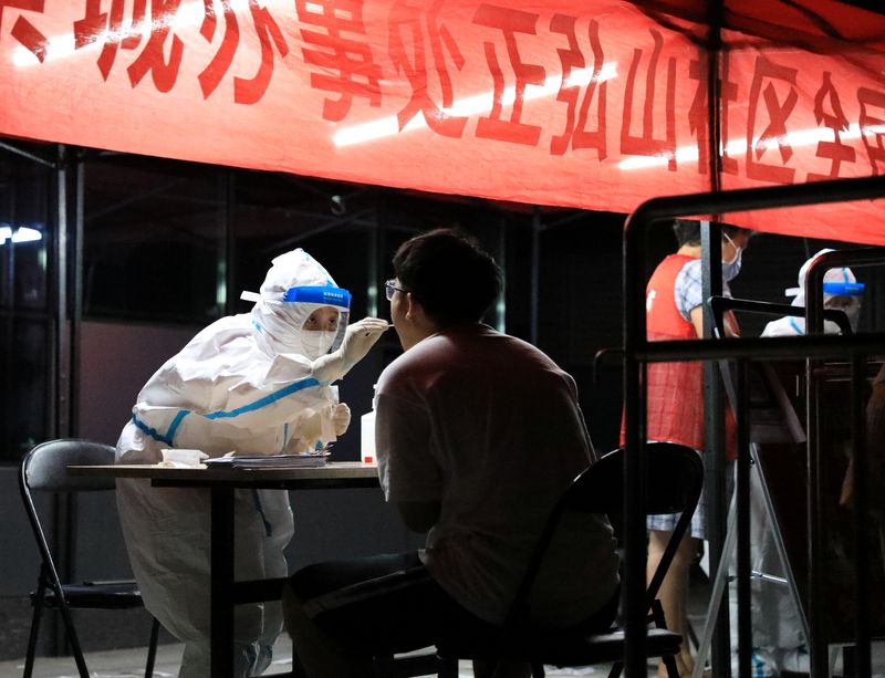 &copy; Reuters. A medical worker in protective suit collects a swab from a resident for nucleic acid testing following new cases of the coronavirus disease (COVID-19) in Zhengzhou, Henan province, China early August 2, 2021. cnsphoto via REUTERS    