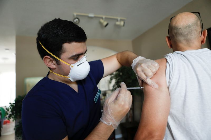 &copy; Reuters. FILE PHOTO: Ledsiel Garcia, a pharmacy technician with DeliveRxd Pharmacy based in Tampa, administers the Pfizer-BioNTech coronavirus disease (COVID-19) vaccine to Mike Payne, a federal employee, at his home in St. Petersburg, Florida, U.S., July 30, 2021