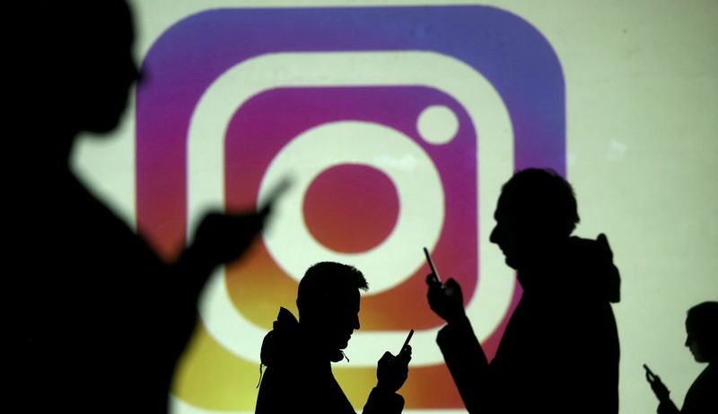 &copy; Reuters. FILE PHOTO: Silhouettes of mobile users are seen next to a screen projection of the Instagram logo in this picture illustration taken March 28, 2018.  REUTERS/Dado Ruvic/Illustration