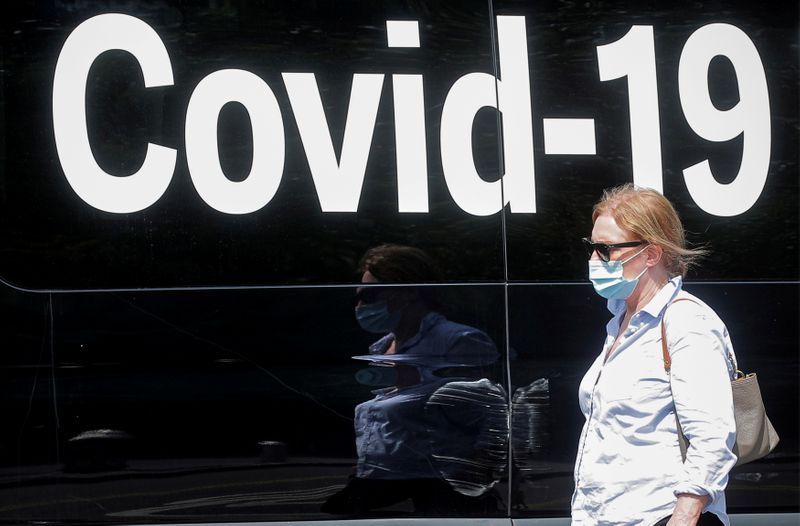 &copy; Reuters. سيدة تضع كمامة تمر أمام مركز متنقل للكشف عن فيروس كورونا في نيويورك يوم 22 يوليو تموز 2021. رويترز