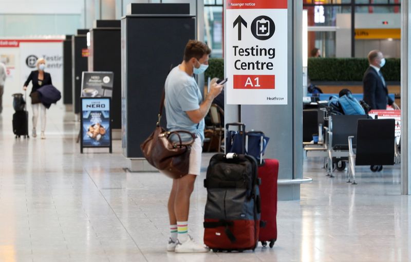 &copy; Reuters. A passenger stands next to a COVID-19 testing centre sign in the International arrivals area of Terminal 5 in London's Heathrow Airport, Britain, August 2, 2021.  REUTERS/Peter Nicholls