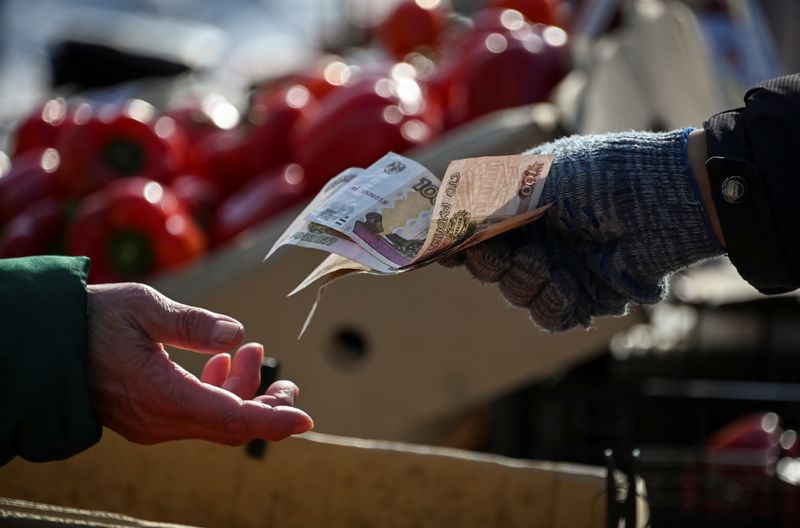 © Reuters. A vendor hands over Russian rouble banknotes to a customer at a street market in Omsk, Russia March 31, 2021. REUTERS/Alexey Malgavko