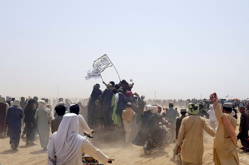 &copy; Reuters. FILE PHOTO: People standing on a vehicle hold Taliban flags as people gather near the Friendship Gate crossing point in the Pakistan-Afghanistan border town of Chaman, Pakistan July 14, 2021.   REUTERS/Abdul Khaliq Achakzai 