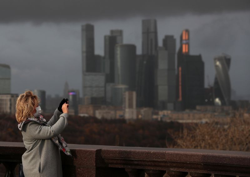 &copy; Reuters. امرأة تضع كمامة تلقتط صورا في موسكو يوم السادس من نوفمبر تشرين الثاني 2020. تصوير: إيفجينيا نوفوتشنينا - رويترز