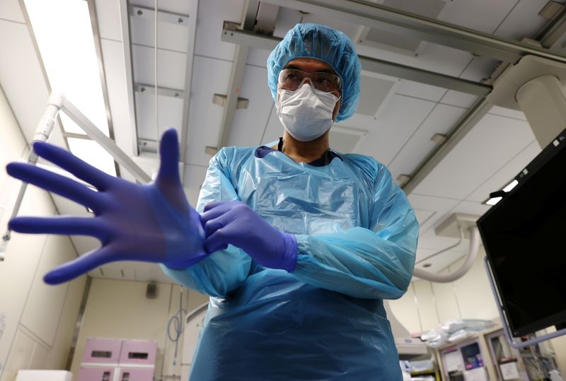 &copy; Reuters. Nippon Medical School Hospital's ICU doctor Shoji Yokobori demonstrates how to wear protective gear against the coronavirus disease (COVID-19) during an interview with Reuters at the hospital in Tokyo , Japan, August 1, 2021.  REUTERS/Kim Kyung-Hoon