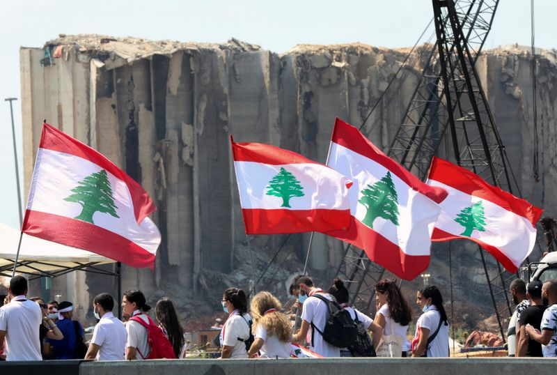 © Reuters. People carry national flags near the site of last year's Beirut port blast, as Lebanon marks the one-year anniversary of the explosion in Beirut, Lebanon August 4, 2021. REUTERS/Mohamed Azakir