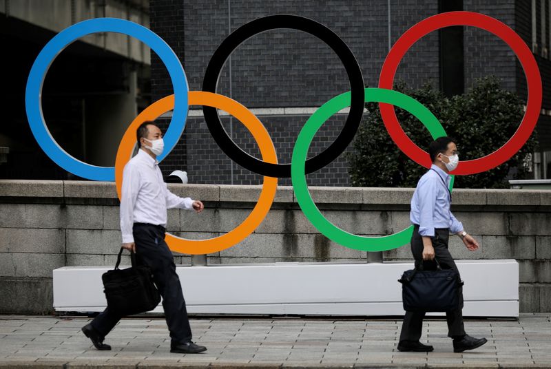 &copy; Reuters. رجلان يضعان كمامتين ويسيران أمام شعار الألعاب الأولمبية في منطقة نيهونباشي التجارية بالعاصمة طوكيو اثناء الألعاب الأولمبية وتفشي فيروس كو