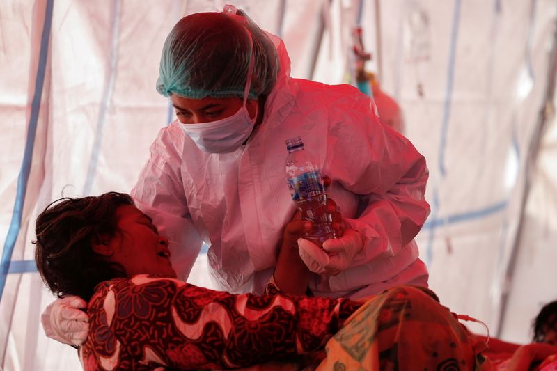 &copy; Reuters. FILE PHOTO: A healthcare worker in personal protective equipment (PPE) treats a patient inside a temporary tent erected outside the emergency ward for accommodating the lack of beds at a government-run hospital amid the surge of coronavirus disease (COVID