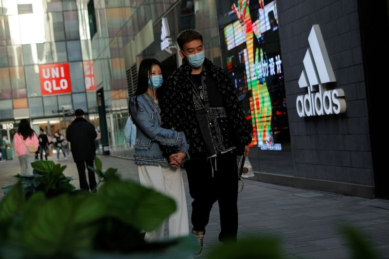 &copy; Reuters. FOTO DE ARCHIVO: Personas pasan por delante de una tienda de Adidas en una zona comercial de Pekín, China, el 28 de marzo de 2021. REUTERS/Thomas Peter