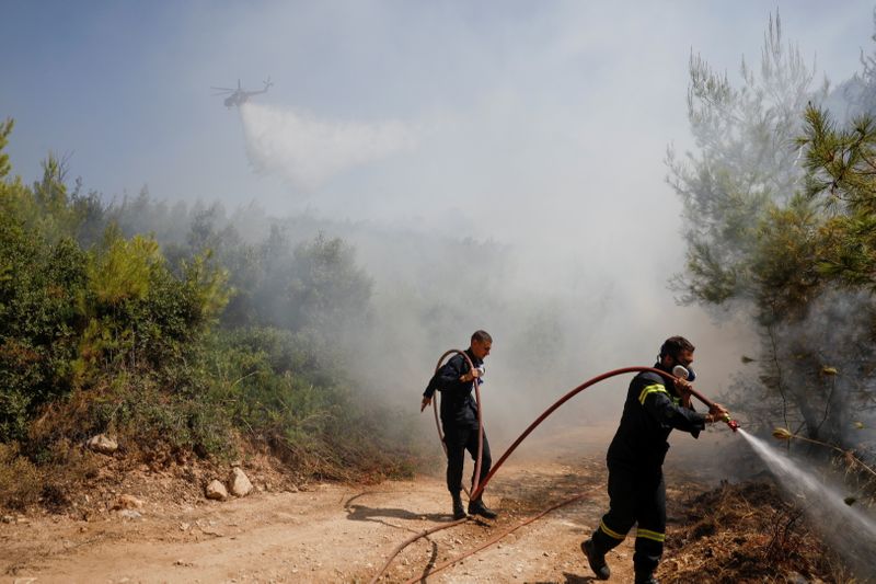 &copy; Reuters. FILE PHOTO: Firefighters spray water to extinguish a wildfire near the village of Rodopoli, north of Athens, Greece, July 27, 2021. REUTERS/Costas Baltas/File Photo
