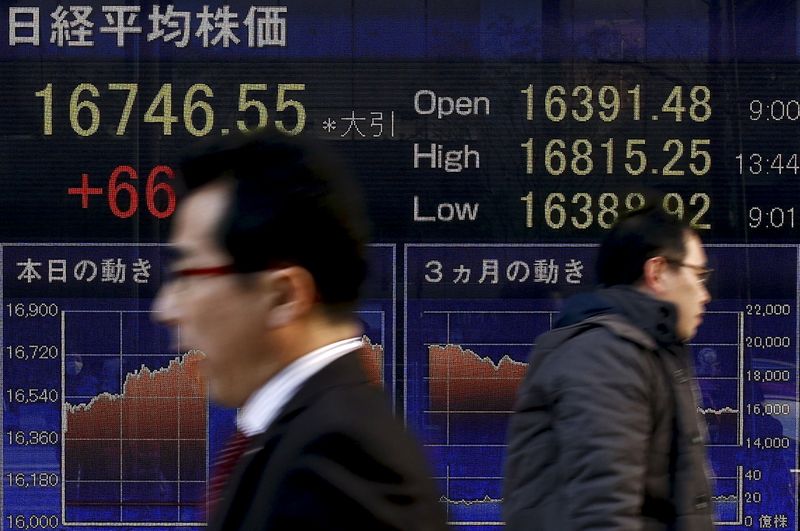 © Reuters. People walk past an electronic board displaying the Nikkei average outside a brokerage in Tokyo, Japan,  March 2, 2016. REUTERS/Thomas Peter