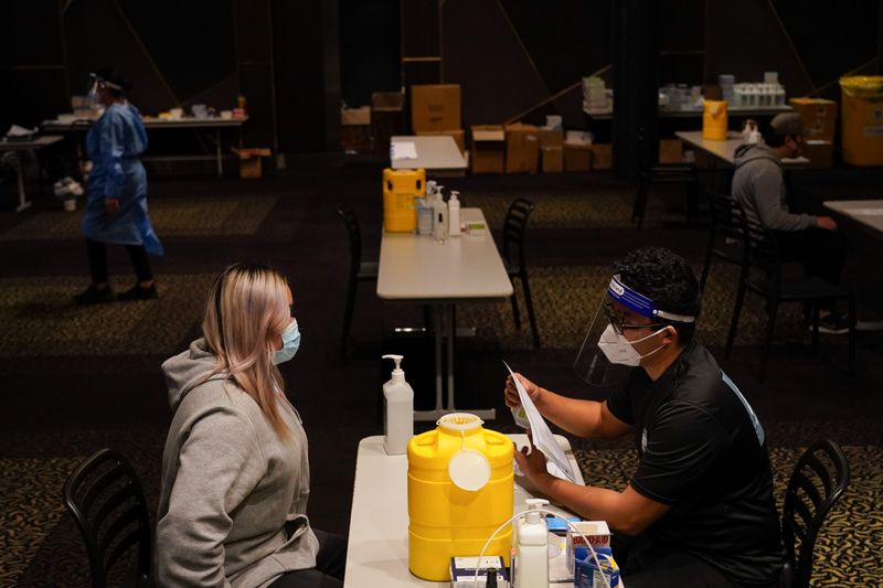 &copy; Reuters. L'infermiere Jude Mendoza prepara la paziente Phiyona Castillo a ricevere il vaccino AstraZeneca in una clinica per la vaccinazione contro il coronavirus ( COVID -19) presso il Bankstown Sports Club, a Sydney, Australia, il 3 agosto 2021. REUTERS/Loren El