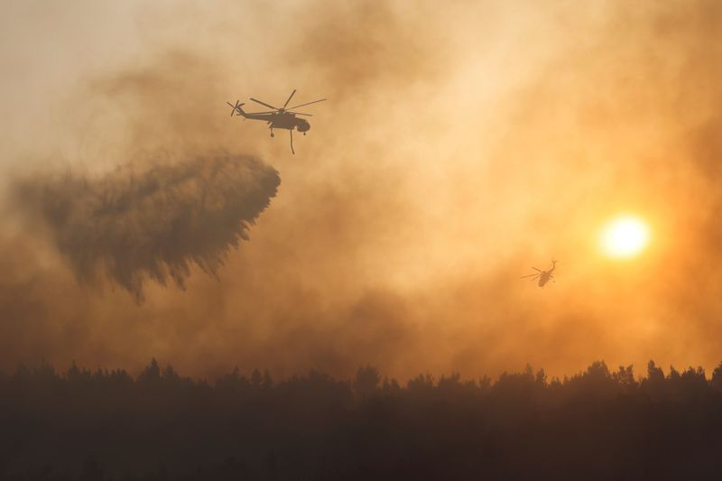 &copy; Reuters. A firefighting helicopter makes a water drop as a wildfire continues to rage at Varympompi suburb north of Athens, Greece, August 4, 2021. REUTERS/Giorgos Moutafis   