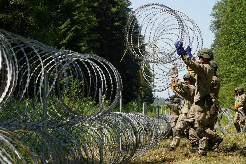 © Reuters. جنود من ليتوانيا يضعون سلكا شائكا على الحدود مع روسيا البيضاء لمنع عبور المهاجرين غير الشرعيين  - صورة من أرشيف رويترز
