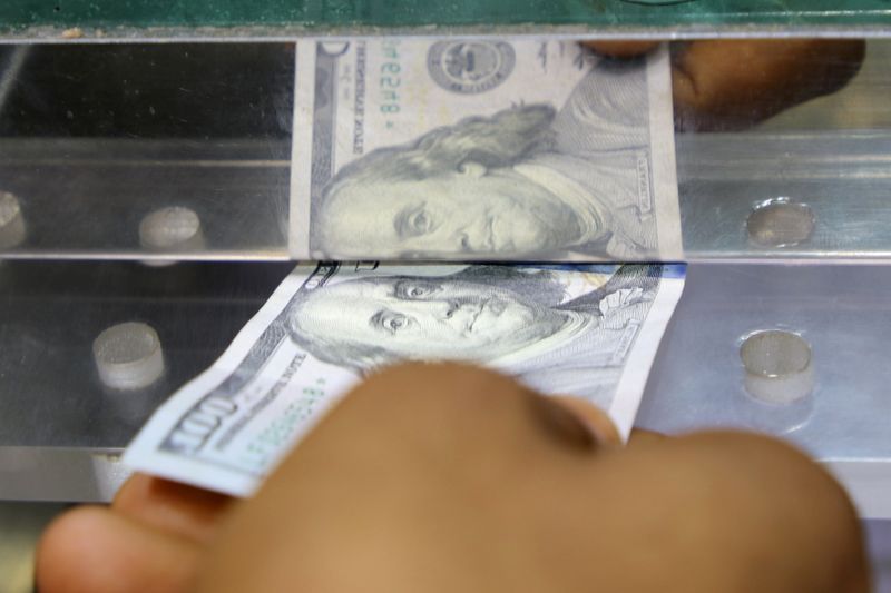 &copy; Reuters. رجل يضع ورقة مالية من الدولار الأمريكي في نافذة مكتب صرافة في عدن يوم 29 يونيو حزيران 2021. تصوير: فواز سلمان - رويترز