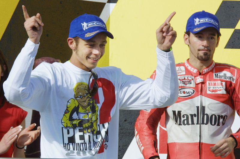 © Reuters. Valentino Rossi festeggia la vittoria del suo primo mondiale nella categoria regina di fronte al rivale Max Biaggi, alla fine del Gran premio d'Australia 2001. Phillip Island, Australia, 14 ottobre 2001. REUTERS/Mark Horsburgh