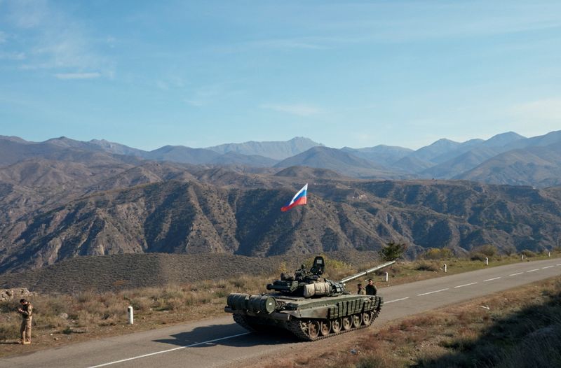 &copy; Reuters. Service members of the Russian peacekeeping troops stand next to a tank near the border with Armenia, following the signing of a deal to end the military conflict between Azerbaijan and ethnic Armenian forces, in the region of Nagorno-Karabakh, November 1