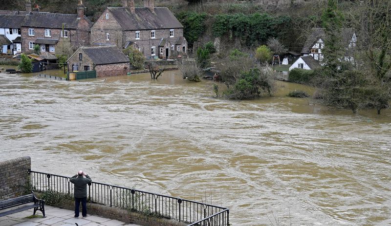 &copy; Reuters. FILE PHOTO: A man views flooded properties beside the River Severn in Ironbridge, Britain, February 27, 2020. REUTERS/Toby Melville/File Photo