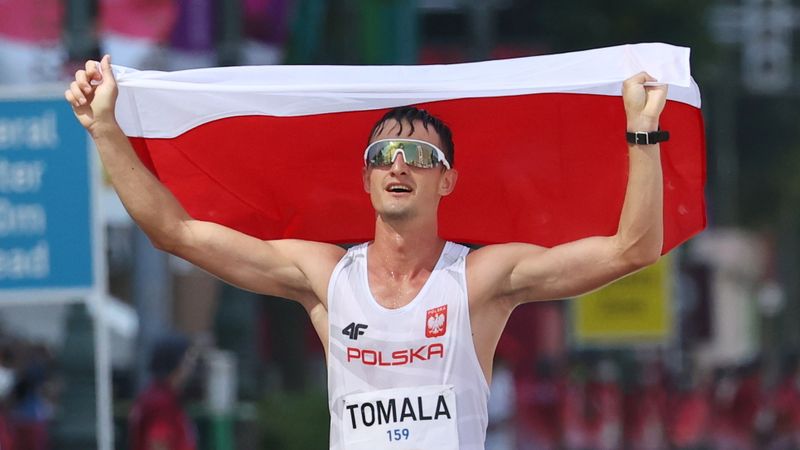 &copy; Reuters. البولندي دافيد تومالا يحمل علم بلاده بعد فوزه بذهبية سباق المشي لمسافة 50 كيلومترا بأولمبياد طوكيو يوم الجمعة. تصوير: كيم هونج جي - رويترز.