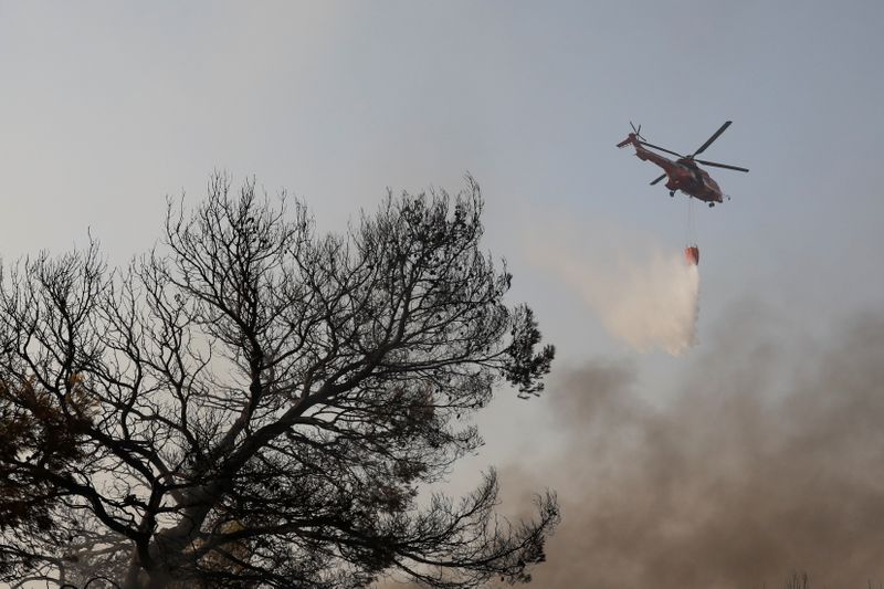 &copy; Reuters. A fire-fighting helicopter makes a water drop as a wildfire burns at Varympompi suburb north of Athens, Greece, August 4, 2021. REUTERS/Costas Baltas
