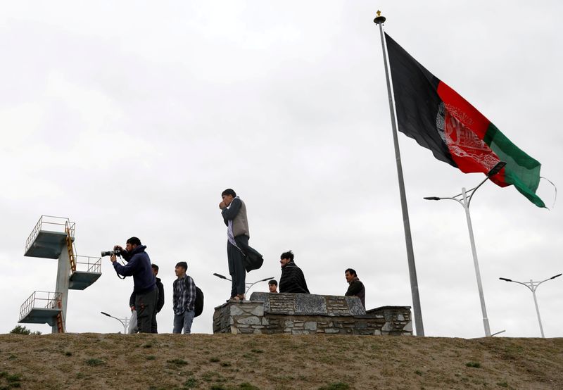 &copy; Reuters. FILE PHOTO: Youths take pictures next to an Afghan flag on a hilltop overlooking Kabul, Afghanistan, April 15, 2021. REUTERS/Mohammad Ismail/File Photo