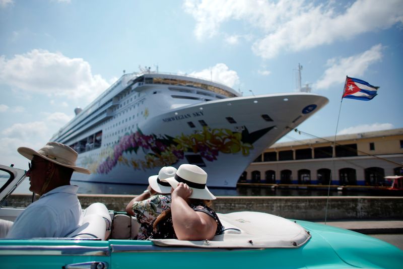 &copy; Reuters. FILE PHOTO: Tourists ride inside a vintage car as they pass by the Norwegian Sky cruise ship, operated by Norwegian Cruise Lines in Havana, Cuba, May 7, 2019. REUTERS/Alexandre Meneghini
