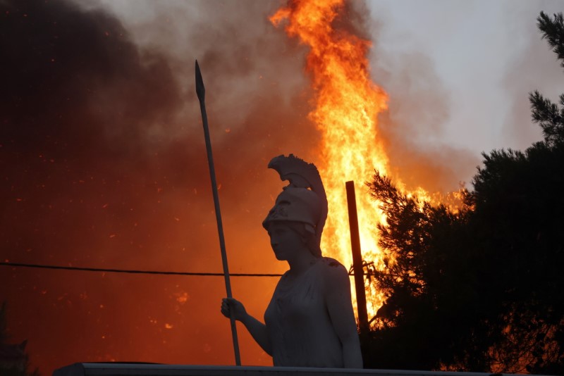 &copy; Reuters. Una estatua con el fuego de fondo en el suburbio de Varympompi en el norte de Atenas, Grecia. 3 de agosto de 2021. REUTERS/Giorgos Moutafis