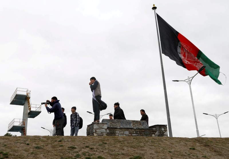 &copy; Reuters. FILE PHOTO: Youths take pictures next to an Afghan flag on a hilltop overlooking Kabul, Afghanistan, April 15, 2021. REUTERS/Mohammad Ismail/File Photo