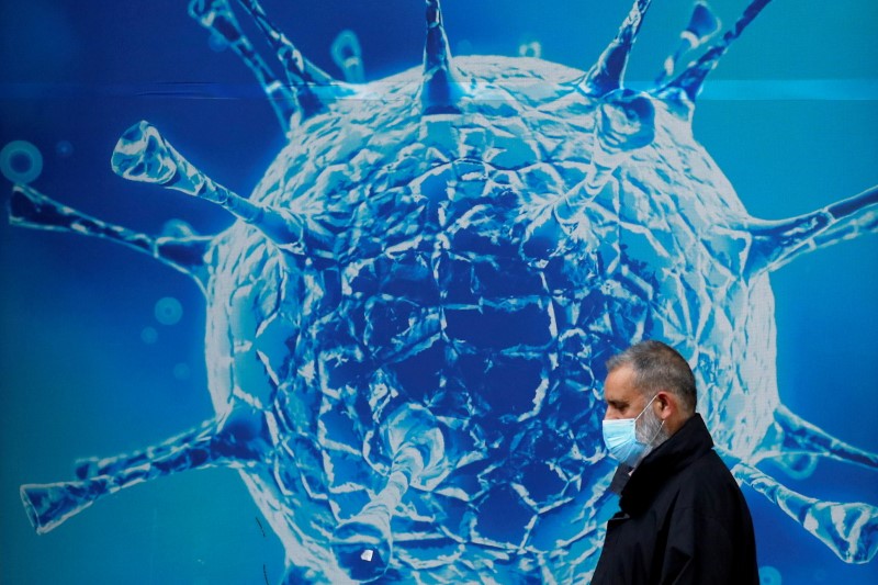 &copy; Reuters. FILE PHOTO: A man wearing a protective face mask walks past an illustration of a virus outside a regional science centre amid the coronavirus disease (COVID-19) outbreak, in Oldham, Britain August 3, 2020. REUTERS/Phil Noble/File Photo