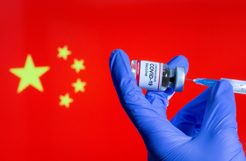 &copy; Reuters. FILE PHOTO: A woman holds a small bottle labeled "Coronavirus COVID-19 vaccine" along with a medical syringe in front of a Chinese flag in this illustration taken, October 30, 2020. REUTERS/Dado Ruvic/File Photo